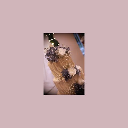 White Wedding cake with buttercream designs and purple and white flowers by Remnant Fellowship Wedding Cake Committee