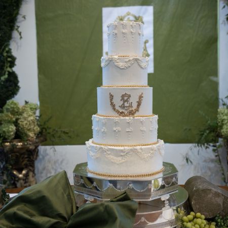 McDonald Covenant Wedding A white five tiered wedding cake with unique fancy piping and gold monogram with gold laurel leaf