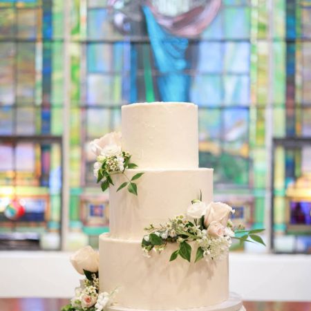 White Three Tiered cake with Rose florals and greenery by Remnant Fellowship Cake Committee