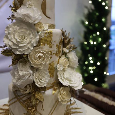 White Tiered Wedding Cake with White florals and gold details by Remnant Fellowship Cake Committee