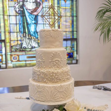 Young/Garcia Covenant Wedding White Detailed Tiered Wedding cake with pearl designs and textured buttercream designs and gold diamond monogrammed cake topper by the Remnant Fellowship Cake Committee