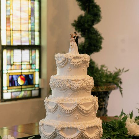 MartinHahn Covenant Wedding White four tiered cake with detail frosting piping and a bride and groom cake topper by the Remnant Fellowship Cake Committee