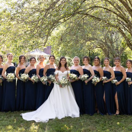 Rolfes/Parson Covenant Wedding A group of bridesmaids wearing long strapless navy dresses and white rose bouquets