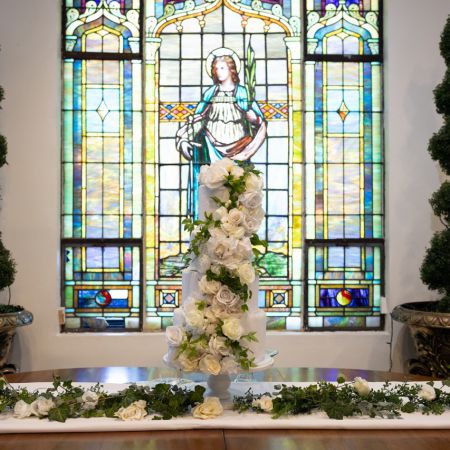 White Three Tiered Wedding Cake With Roses and greenery designed by The Remnant Fellowship Cake Team